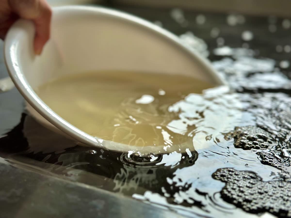 桶で温泉をすくう様子。湯は淡い琥珀色
